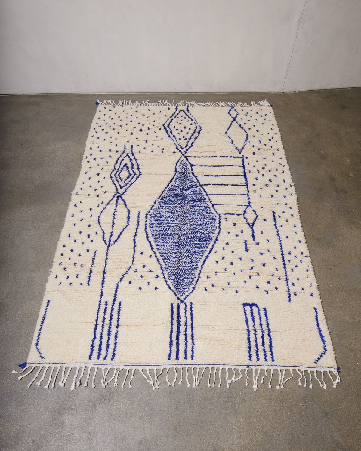 Berberlin Azilal rug made of fluffy wool and blue cotton, laying flat on a concrete floor.